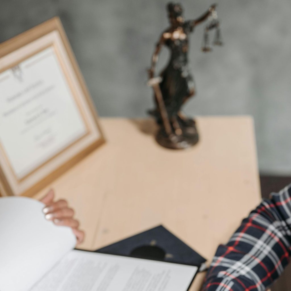 Hands of a person signing official documents on a desk in an office setting.